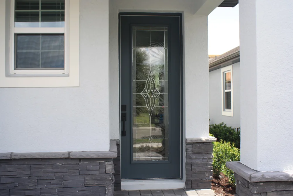 Puerta exterior de entrada con vidrio decorativo en una casa de estuco en Florida