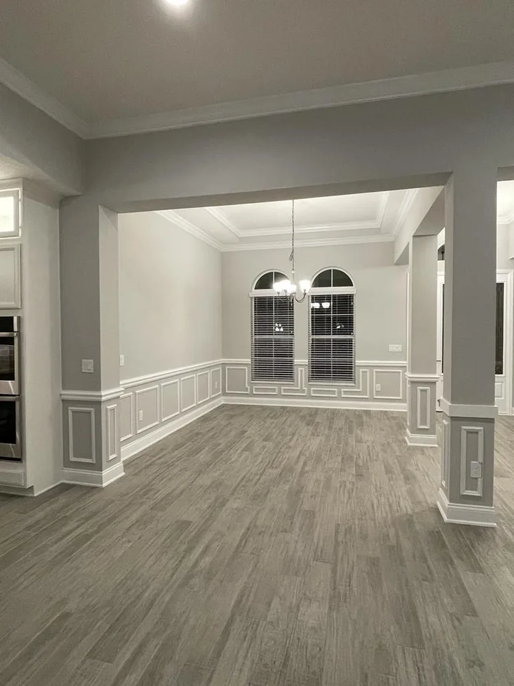 Sala y comedor abiertos con paneles de wainscoting, moldura de silla y corona